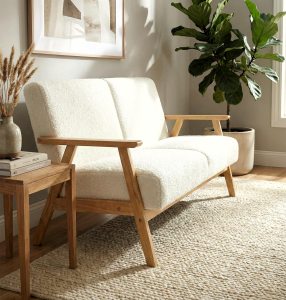 Dwuosobowa sofa na drewnianych nóżkach, odcień biały.