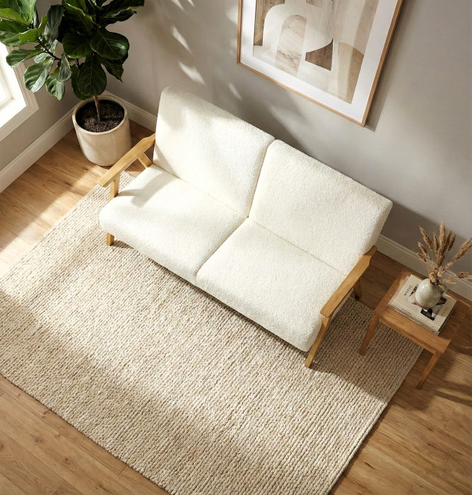 Dwuosobowa sofa na drewnianych nóżkach, odcień biały. Zdjęcie od góry.